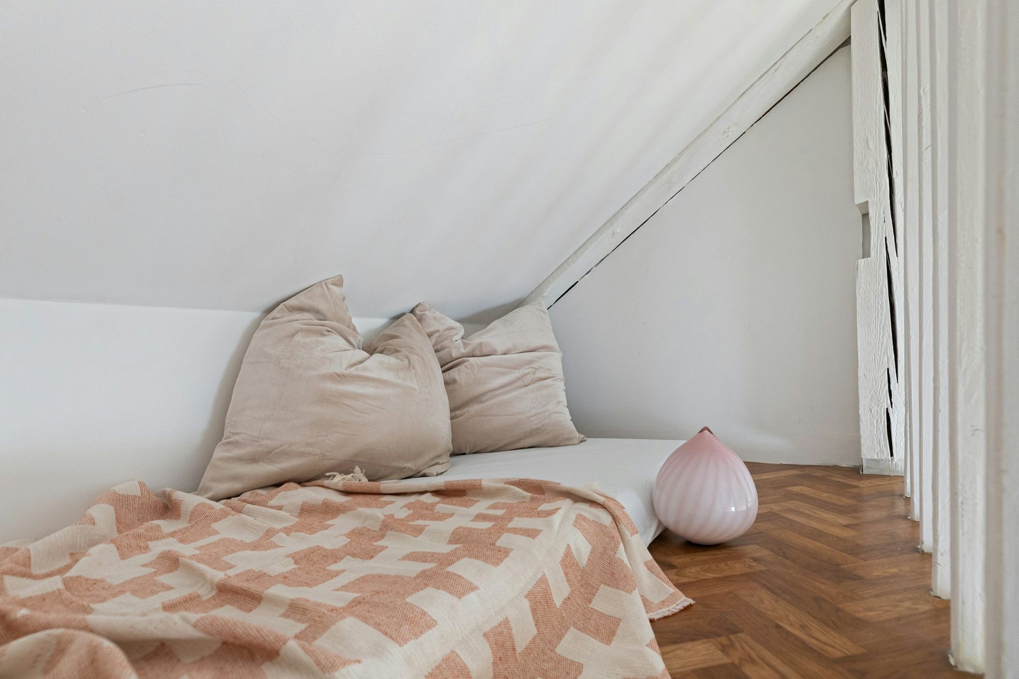 Un angolo tranquillo sotto il tetto, con cuscini morbidi e una coperta dai colori tenui