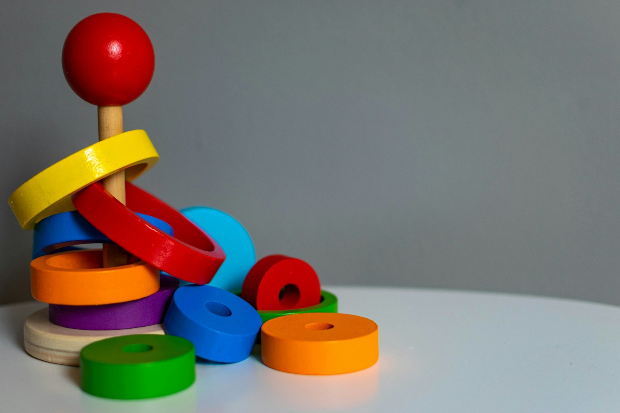 Un gioco di anelli colorati da impilare, con alcuni pezzi sparsi sul tavolo.