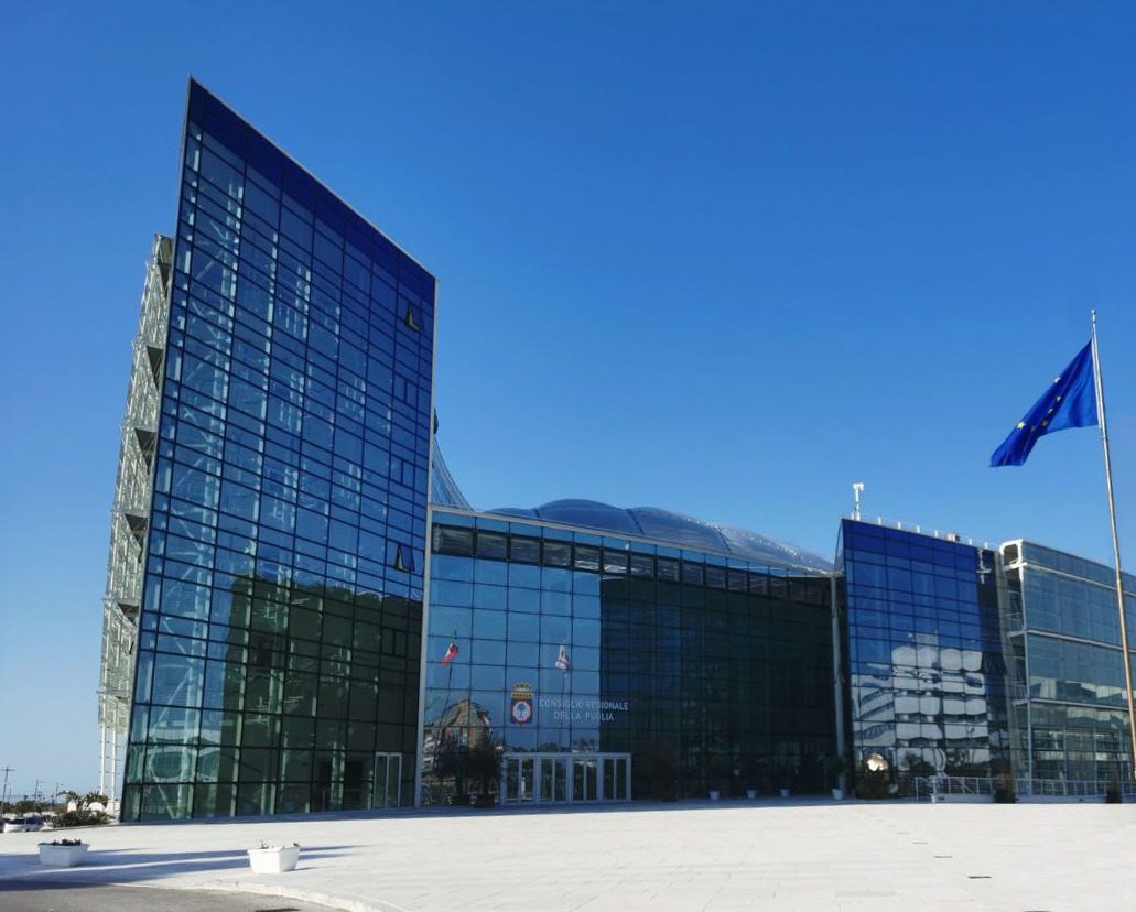 La sede in vetro del Consiglio regionale della Puglia a Bari, con la bandiera europea davanti all'ingresso