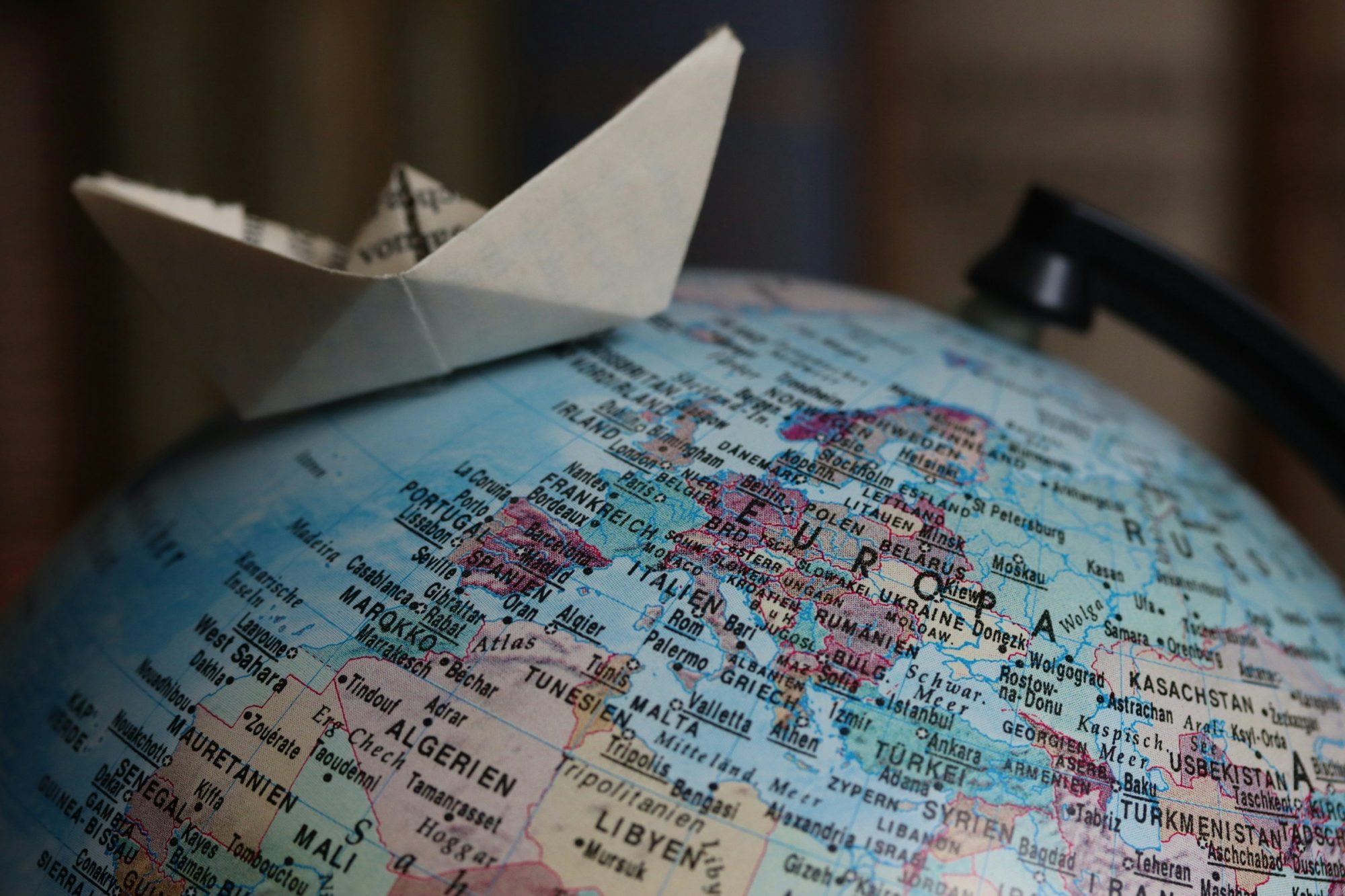 Una barchetta di carta appoggiata sopra un mappamondo