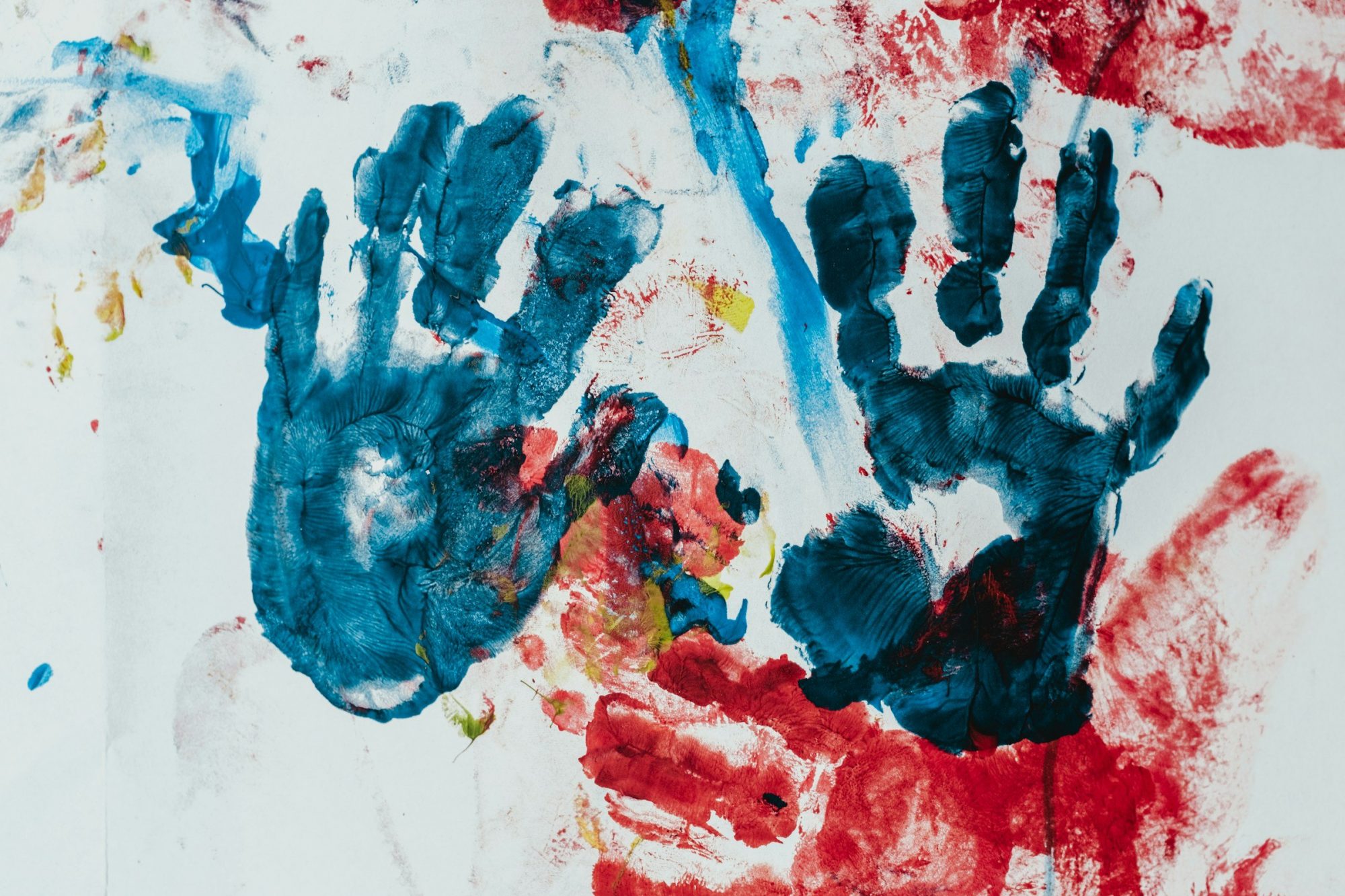 Impronte colorate di mani di diverse misure dipinte una accanto all'altra su un foglio bianco.