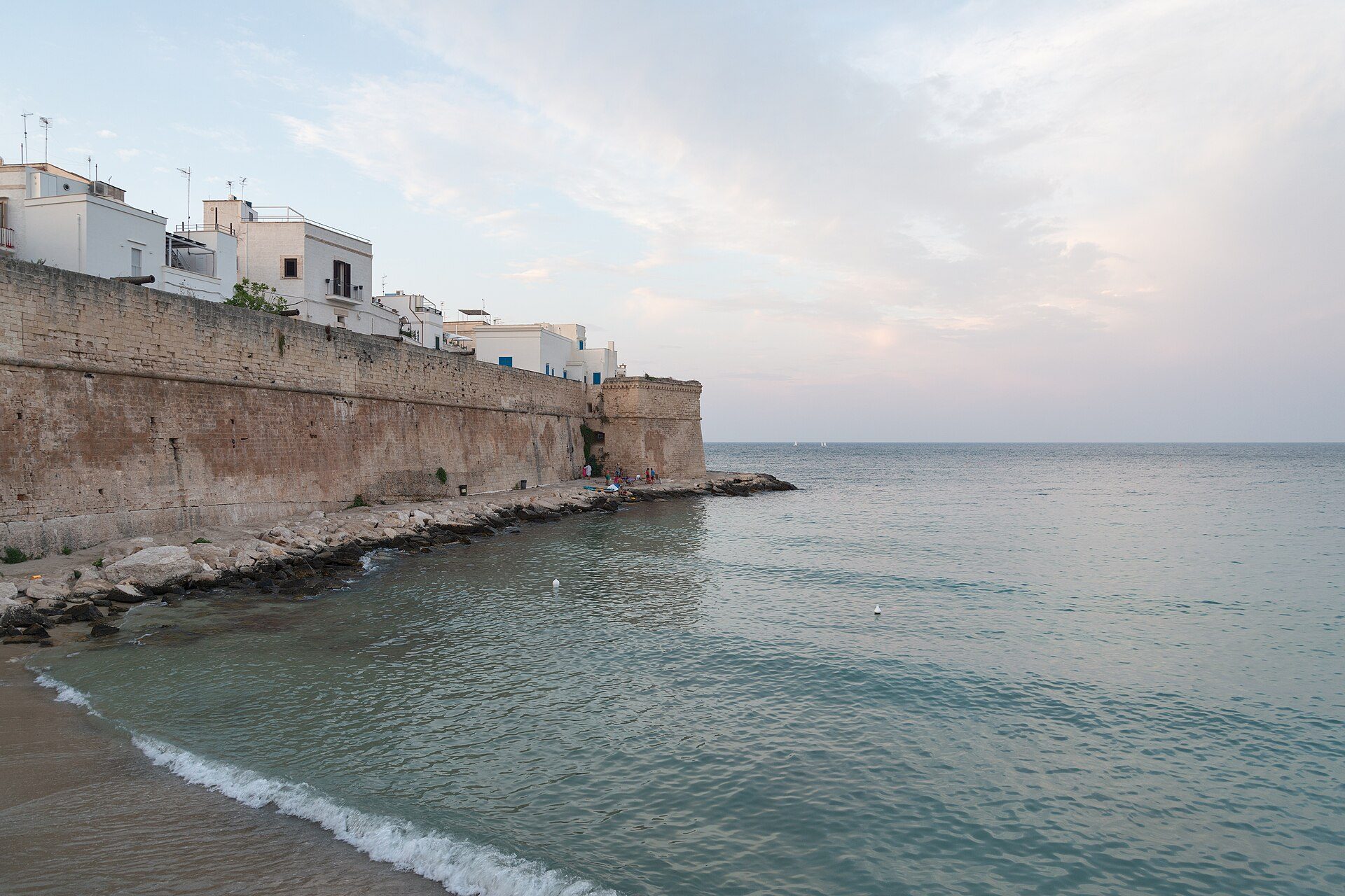 Case bianche sulle mura di Monopoli affacciate sul mare al tramonto