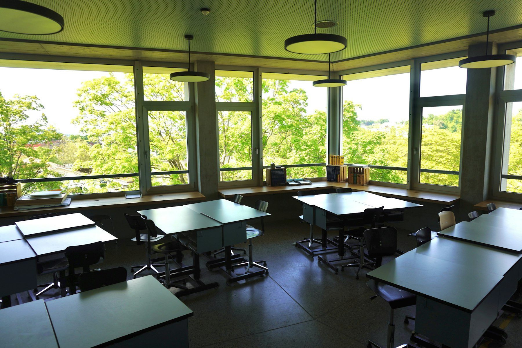 Un'aula scolastica vuota e luminosa, con banchi, sedie e grandi finestre.