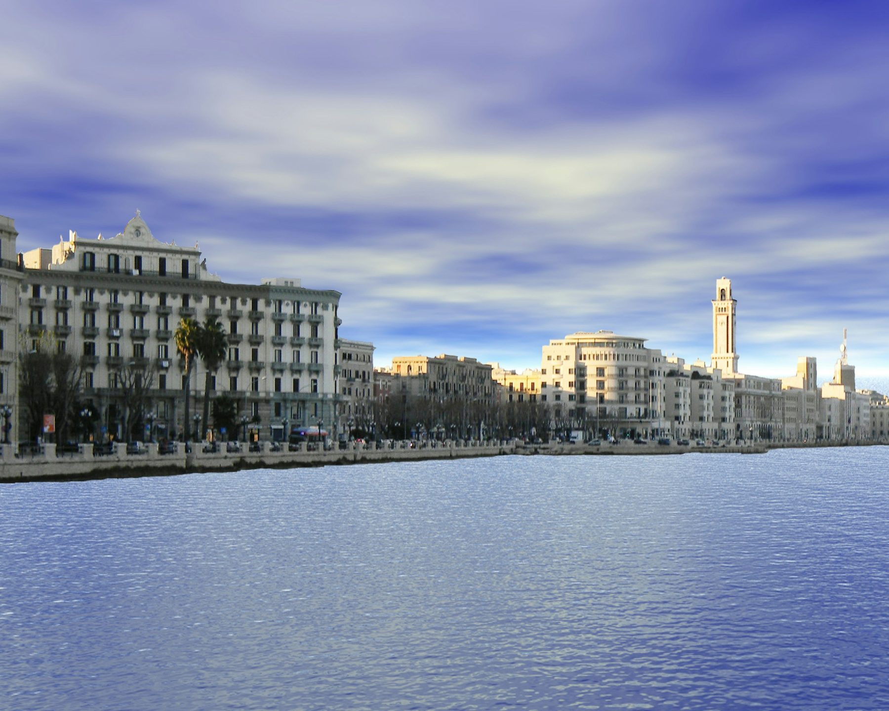 Il lungomare di Bari visto dall'acqua, con i palazzi affacciati sul mare sotto un cielo mosso